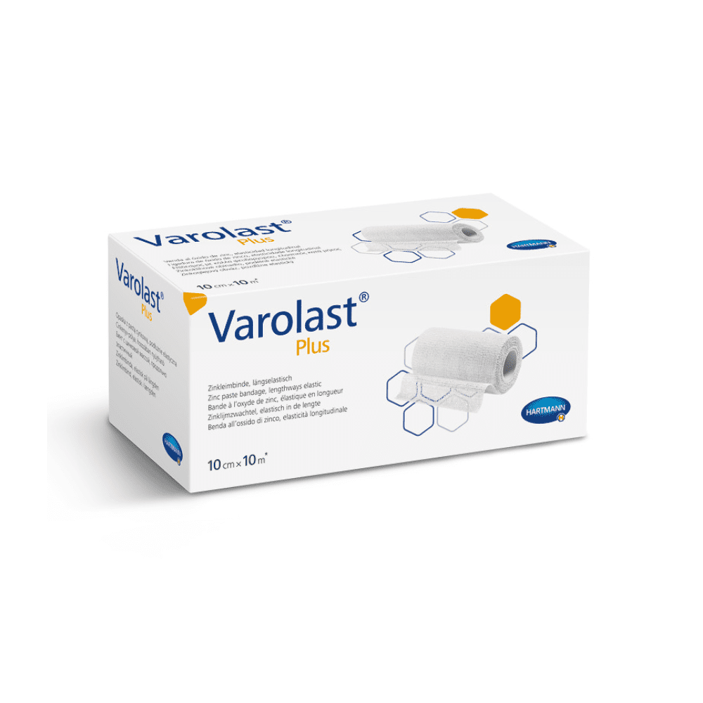 La imagen muestra una caja blanca rectangular que contiene una venda de zinc Hartmann Varolast® Plus. El envase presenta una imagen de una venda enrollada y motivos hexagonales. Ideal para el tratamiento de edemas y flebitis; las medidas indicadas en la caja son 10 cm x 10 m. En la parte inferior derecha se aprecia el logotipo de Paul Hartmann AG.