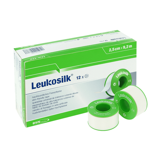 Abgebildet ist eine Schachtel BSN Medical GmbH Leukosilk Rollenpflaster (9,2 m x 2,5 cm, Packung mit 12 Rollen) mit drei weißen Bändern auf grünen Spulen; Die mehrsprachige Box hebt die einfache Fixierung von Verbänden hervor und ist rückstandslos entfernbar.
