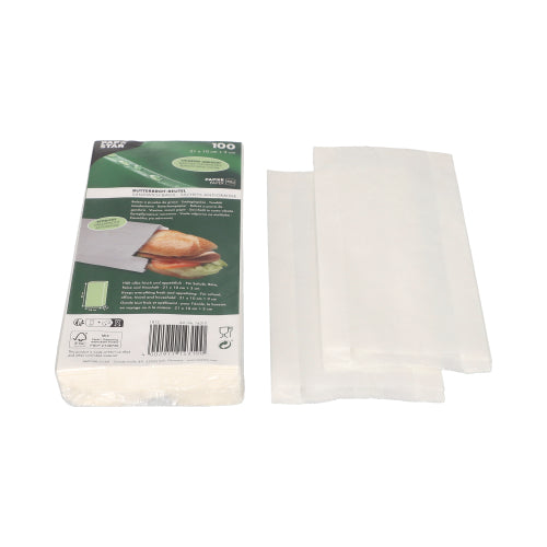 Se muestra una pila de bolsas de papel encerado blancas PAPSTAR (21x10x3 cm) junto al embalaje verde y blanco de PAPSTAR GmbH, que muestra un sándwich y una información del producto. Junto al paquete (100 unidades) hay algunas bolsas de celofán parcialmente desplegadas.