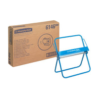 Una caja con la inscripción «Kimberly-Clark Professional™ Soporte de pared para rollos de paños de limpieza - Rollo grande», de Kimberly-Clark GmbH, se encuentra junto a su marco dispensador azul; ambos sobre un fondo blanco.