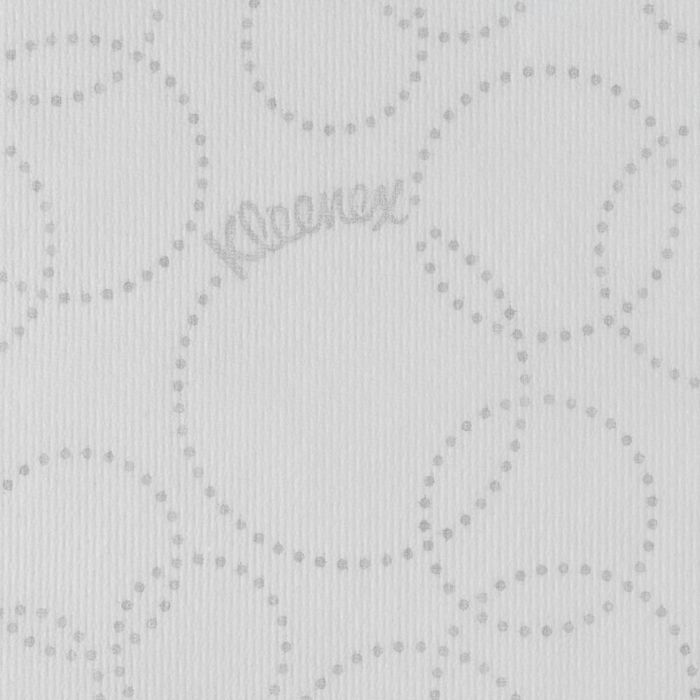El primer plano de una toalla de papel Kleenex® Ultra™ MultiFold blanca de Kimberly-Clark GmbH muestra un patrón circular punteado en gris claro, un sutil logotipo de "Kleenex" entre los puntos y una textura ligeramente acanalada.