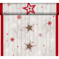 El Dunicel-Tete a Tete de 0,4 x 24 m, de Duni GmbH, presenta estrellas rojas, blancas y marrones con copos de nieve sobre un fondo de madera clara con un borde rojo; es ideal como elegante camino de mesa para cualquier decoración festiva.
