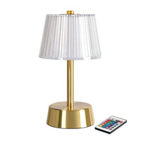 La lámpara LED «Jay Messing» de Duni GmbH, una lámpara de mesa de bajo consumo con base dorada y pantalla transparente plisada, se suministra con un mando a distancia para seleccionar el color. Incluye 1 unidad.