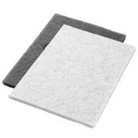 Two Twister Pads, 14x20" white (35x51 cm), from Diversey Deutschland GmbH & Co. OHG, Step 1, lie flat on a white background: the white pad on top, slightly overlapping a dark gray pad. Ideal for professional use.
