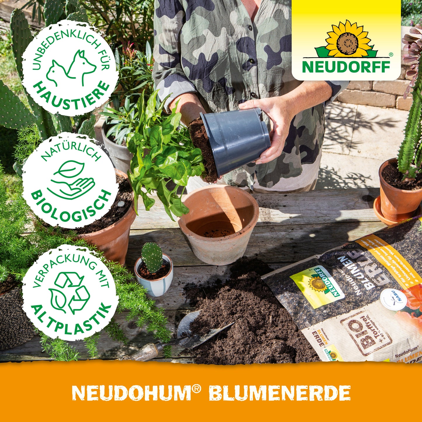 Eine Person beim Umtopfen einer Pflanze an einem Tisch mit Erde, getopften Gartenpflanzen, Gartengeräten, Blumenerde-Taschen und einer NeudoHum BlumenErde-Tasche von Neudorff Shop. Neben dem Neudorff-Logo erscheinen die Symbole für Umweltfreundlichkeit und Haustierfreundlichkeit.