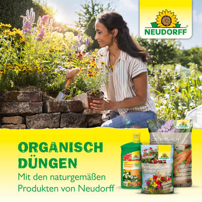 Eine Frau pflanzt mit einer Kelle Blumen neben einem Hochbeet. Davor stehen Azet VeggieDünger von Neudorff Shop. Der deutsche Text wirbt für organisches Düngen mit dem natürlichen Azet VeggieDünger von Neudorff Shop.