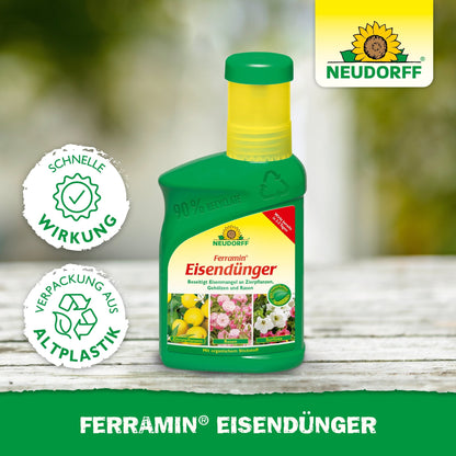 A green plastic bottle with Ferramin iron fertilizer from Neudorff Shop stands on a wooden surface. The label features flowers and lemons, advertising quick action against nitrogen deficiency and noting that it is packaged in recycled plastic.