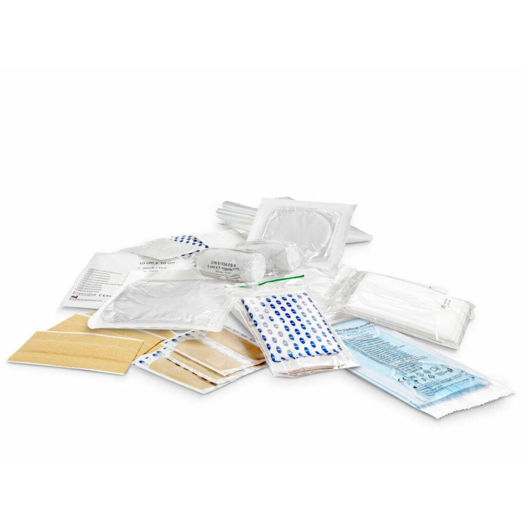 Sterile medical bandages, bandages, and gauze bandages from the DIN-Mine set | Pack (1 piece) by Orkla Wound Care AB are neatly arranged in individual packages on a white surface, reflecting the organized precision of DIN-Mine stationery.