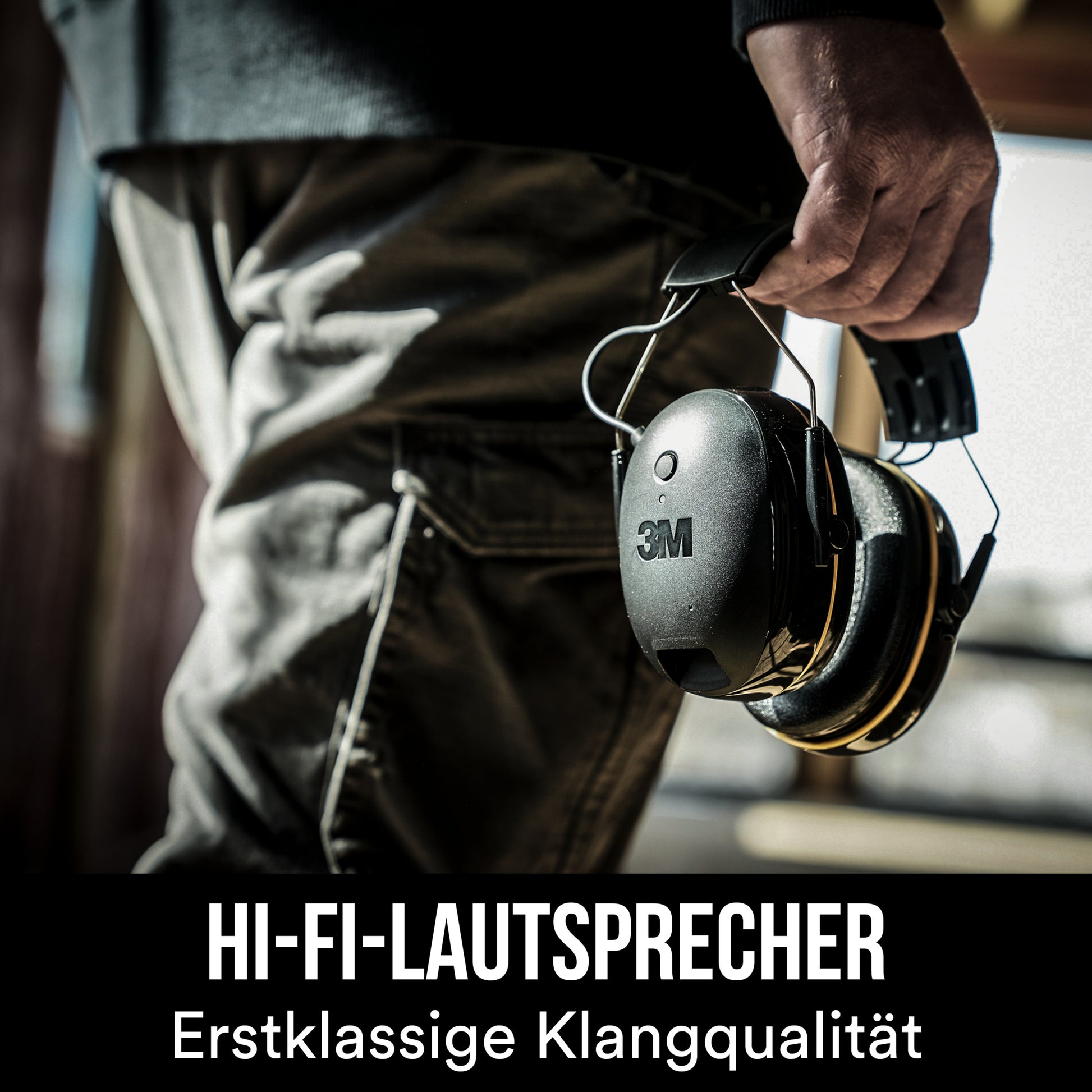 Eine Person in dunkler Kleidung hält den 3M™ WorkTunes™ Connect Kapselgehörschutz 90543E (Bluetooth®, SNR 31 dB, Schwarz) von 3M Deutschland GmbH. Text unten: "HI-FI-LAUTSPRECHER Erstklassige Klangqualität.