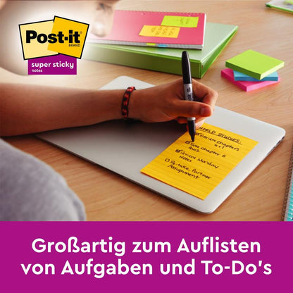 On a closed laptop, someone writes tasks on a yellow Post-it® Super Sticky Note in large format (101x152mm, lined). Colored notebooks, a pen, and multicolored 3M Super Sticky Notes are next to it. Text: "Great for listing tasks and to-dos."