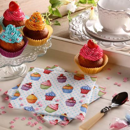 Et bord er dekket med cupcakes på et glassfat, en tallerken, skje, hvit tekopp og skål, rosa hjerteformet strøssel og fargerike PAPSTAR 20 servietter 33x33cm 3-lags 1/4-fals design sett 5 fra PAPSTAR GmbH.