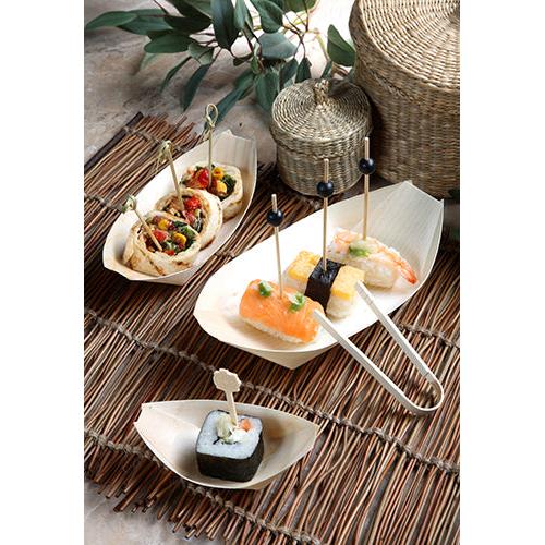 Fingerfood wie Sushi und Wraps auf Spießen wird in PAPSTAR 50 Fingerfood-Schalen Holz „pure“ Schiffchen von PAPSTAR GmbH auf einer Bambusmatte mit Körben und grünen Blättern im Hintergrund serviert.