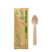 An environmentally friendly PAPSTAR Wooden coffee spoon, 11 cm, individually wrapped in shrink wrap, lies next to its "pure" packaging with the brand's green lettering PAPSTAR GmbH on a plain white background.