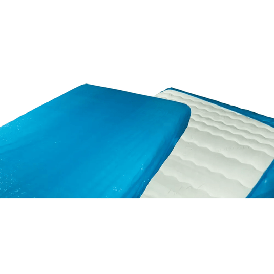 Primer plano de un cubrecolchón de gel azul y blanco, similar al protector de colchón desechable AMPri MED-COMFORT PE con elástico de 210 x 90 x 20 cm de AMPri Handelsgesellschaft mbH. La parte azul cubre la mayor parte de la superficie superior, mientras que la parte blanca presenta una textura ondulada. La imagen muestra una parte doblada hacia atrás, de forma similar a los protectores de colchón de polietileno utilizados en hospitales.