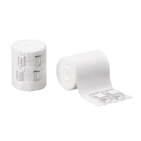 The picture shows two rolls B. Braun Askina® Ideal DIN-Ideal Bandage by B. Braun Deutschland GmbH & Co. KG. One roll is securely wrapped with metal clips, while the other is partially unrolled, revealing its textured, skin-friendly cotton surface. Next to them are two separate metal clips, all set against a plain white background.