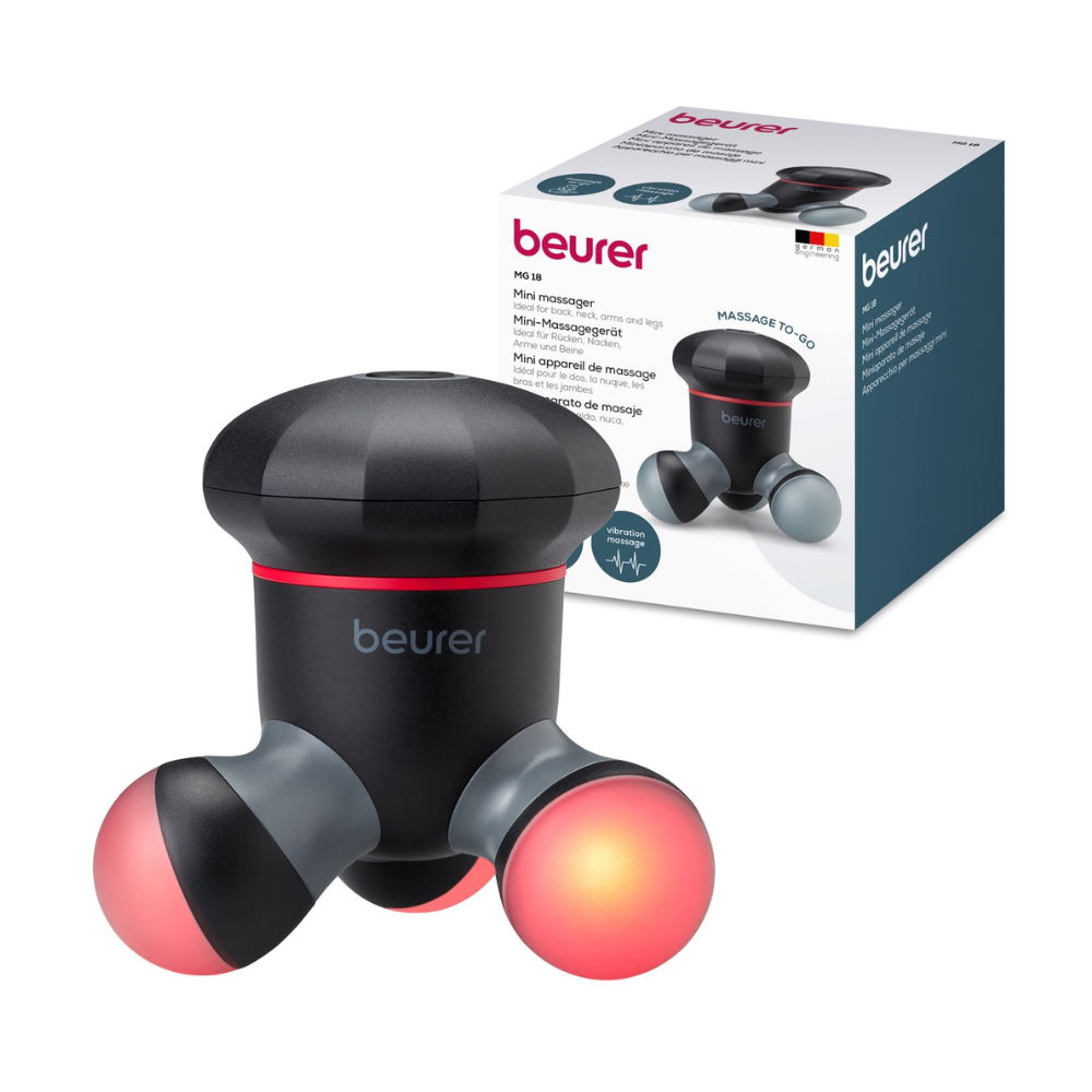 En Beurer mini-massasjeapparat MG 18 | Pakke (1 stk) fra Beurer GmbH er avbildet før emballasjen. Massasjeapparatet, som tilbyr en mild vibrasjonsmassasje, er svart med røde detaljer på håndtakene. Esken i bakgrunnen viser produktinformasjon og et bilde av massasjeapparatet.