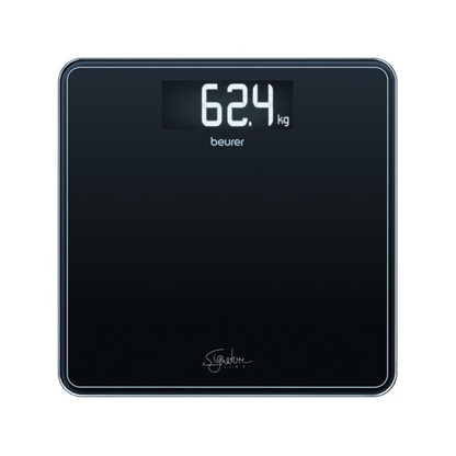 Una báscula corporal GS 400 SignatureLine de Beurer muestra un peso de 62,4 kilogramos en su superficie negra, con una gran pantalla digital clara en la parte superior. Bajo la pantalla se ve la marca 'Beurer GmbH', junto al logo de la báscula de vidrio SignatureLine, que se encuentra en la parte inferior de esta báscula con capacidad de carga de 200 kg.