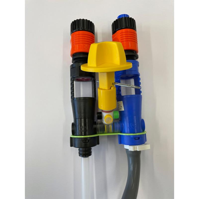 Dos inyectores dosificadores, uno negro y otro azul con punta naranja, están conectados por una banda verde y una tapa amarilla con un tubo gris inferior. Parte del sistema QuattroSelect Manifold Air Gap Oxivir Excel JFill de Diversey Deutschland GmbH & Co. OHG.