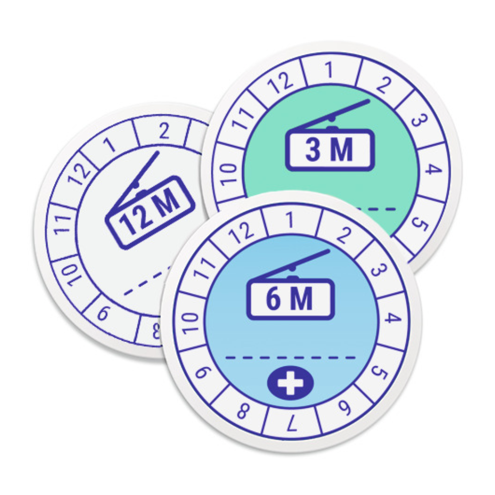 Three round stickers with clock-like design, each indicating different periods of product usability: "12M" in white, "3M" in green, and "6M" in blue. These Hartmann labels for marking usability | Pack (1 piece) by Paul Hartmann AG have numbers on the edges and an inner illustration reminiscent of a dial with a measuring device.