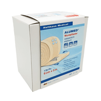 A white box of Holthaus Alumed® adhesive bandages, 6 cm x 5 m, from Holthaus Medical GmbH & Co. KG features an image of the roll of bandages and states that it is hypoallergenic, waterproof, and elastic. The text on the box of the water-repellent adhesive bandages is primarily in German. The product is manufactured in Germany.