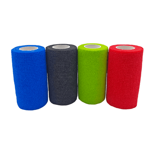 Se ven cuatro rollos de vendaje autoadhesivo Holthaus VliVet® para uso veterinario, de Holthaus Medical GmbH & Co. KG, colocados uno al lado del otro. De izquierda a derecha, los colores son azul, negro, verde y rojo. Los vendajes tienen una superficie texturizada y una forma cilíndrica con un núcleo interior blanco, lo que los hace ideales para el cuidado de las pezuñas en el ámbito veterinario.