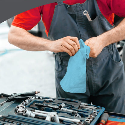 A person in a red shirt and gray overalls uses WypAll® X80 PowerClean cloths from Kimberly-Clark GmbH (BRAG™ Box/Steel Blue, 160 cloths) next to a tool-covered table for industrial cleaning.