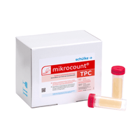 Una caja blanca con la inscripción «Schülke & Mayr GmbH Mikrocount® TPC, medio de cultivo | Envase (20 unidades)», con un logotipo y una descripción del producto junto a dos frascos para pruebas microbianas, uno con tapa amarilla y el otro con tapa transparente.