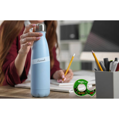 Eine Person hält eine hellblaue Wasserflasche mit der Aufschrift "Hannah" an einem Schreibtisch mit Notizbüchern, Bleistiften, einem Stifthalter und einer Packung 3M Deutschland GmbH Scotch® Magic™ Unsichtbares Klebeband 8-1925R3 (19 mm x 25 m, 3 Rollen/Packung).