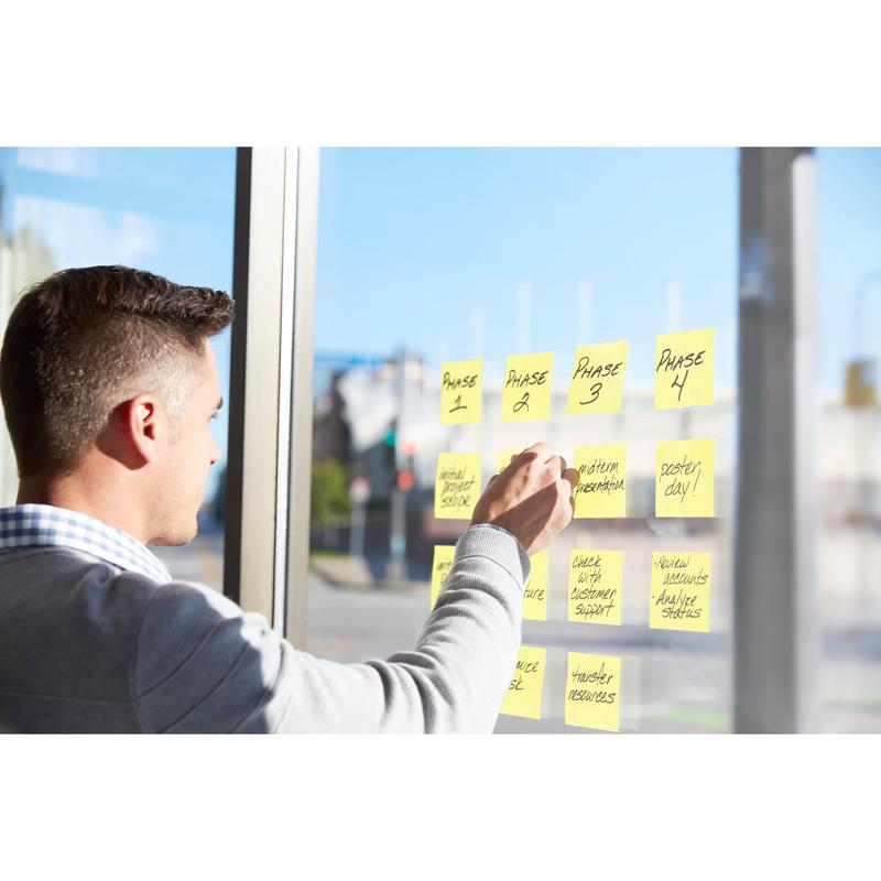A man organizes his work processes at a sunlit window with Post-it® Super Sticky Notes Cubes, Yellow, 76 mm x 76 mm by 3M Deutschland GmbH, marking project phases and tasks for clear visual management.
