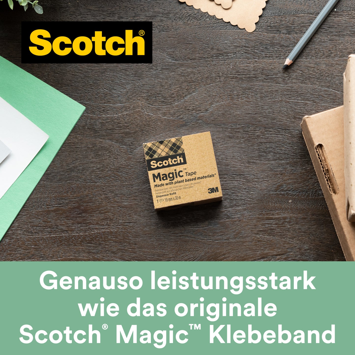Eine Schachtel Scotch® Magic™ Klebeband (19 mm x 30 m, 1 Rolle, mit 66 % pflanzlichem Klebstoff von 3M Deutschland GmbH) liegt auf einem Holztisch neben grün-weißem Papier, einem Stift und einer Notizkarte. "Genauso leistungsstark wie das originale unsichtbare Klebeband.