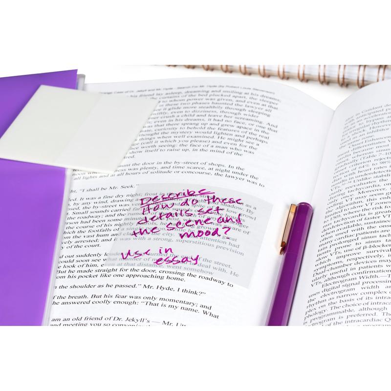 Un libro abierto con notas manuscritas en Notas Transparentes Post-it® (73x73 mm, 36 hojas, de 3M Deutschland GmbH), un bolígrafo morado y una carpeta morada. En la nota dice: "Describe cómo estos detalles representan la escena en el estado de ánimo. Use in essay."