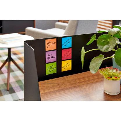 Et nærbilde av en skrivebordsavdeling med seks fargerike Post-it® Super Sticky Notes (76 mm x 76 mm, 90 ark/blokk, 100% PEFC) fra 3M Deutschland GmbH, som viser detaljer. En grønnplante og uskarpt kontormøblement fullfører scenen.