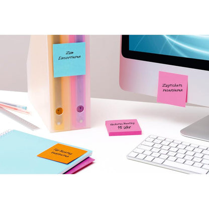 Et ryddig skrivebord med en datamaskin, et tastatur, to permer, en notatbok og 3M Deutschland GmbH Post-it® Super Sticky Notes (76mm x 76mm, 90 ark/blokk, 100% PEFC) med tyske påminnelser for møter og reservasjoner.