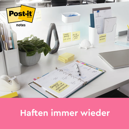 Auf einem aufgeräumten Bürotisch liegen ein offener Planer, Schreibwaren, eine Pflanze und gelbe Post-it® Notes (38 x 51 mm, 16+4 Promo Pack von 3M Deutschland GmbH) auf der Trennwand. Ein Laptop ist teilweise sichtbar. Darunter steht auf einem rosa Banner "Haften immer wieder".